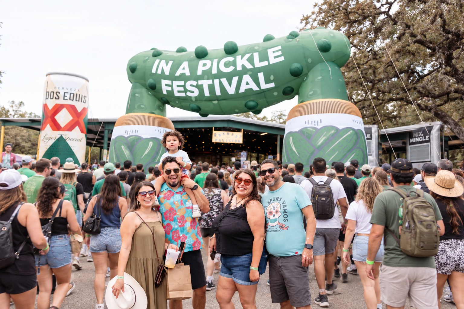 A crowd of festival guests arriving beneath the giant In A Pickle Festival entrance